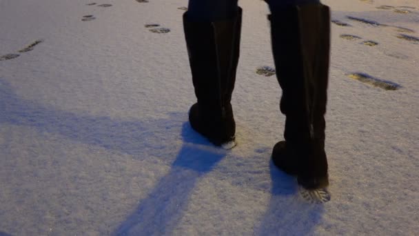 Eine Frau in Stiefeln tritt auf den Schnee und hinterlässt Spuren im Schnee — Stockvideo