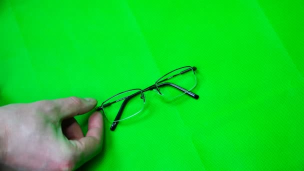Врач кладет очки с лупой на зеленый фон — стоковое видео