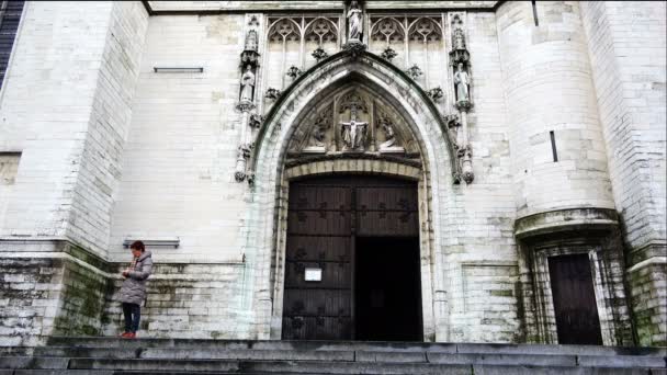 Vrouw staat bij de ingang naar de tempel in de gotische stijl — Stockvideo