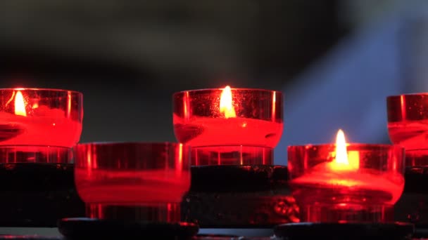 Brandende kaarsen in rood kandelaars in de tempel — Stockvideo