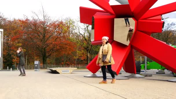 Uma mulher é fotografada em uma escultura de espelho de cor vermelha — Vídeo de Stock
