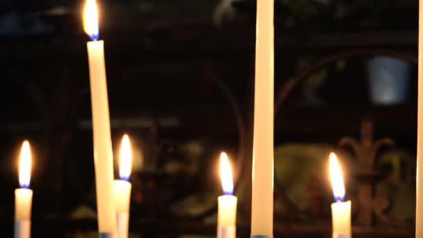 Lichter brennender weißer Kerzen in einem Tempel auf dunklem Hintergrund — Stockvideo