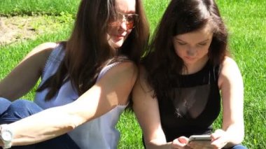 Anne ve kızı parkta bilgi teknolojisi cep telefonu kullanmak