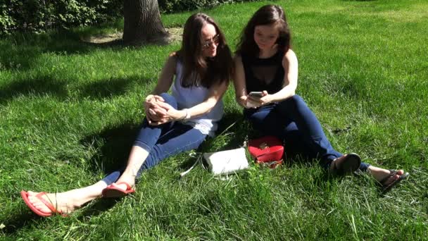 A girl shares photos on a smartphone and has fun with her friend — Stock video