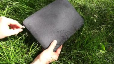 yeşil çimenlerin üzerinde beyaz bir dizüstü bilgisayar kapağı dışarı almak