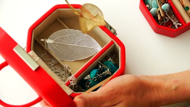 Η γυναίκα βάζει τα κοσμήματα σε ένα κόκκινο διακοσμητικό κουτί — Αρχείο Βίντεο