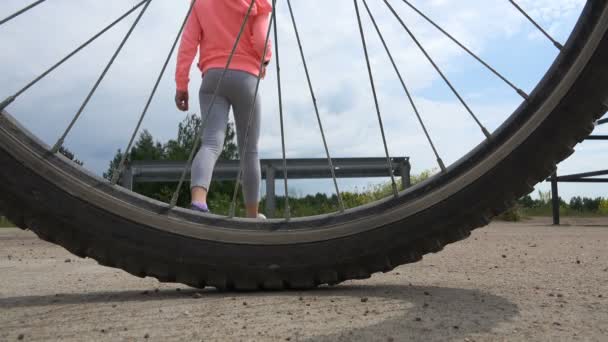 Una chica está caminando detrás de un volante de una bicicleta de pie — Vídeo de stock