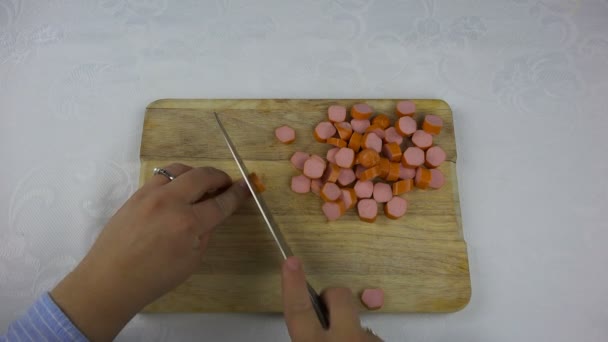 Couper une saucisse en travers avec un couteau sur une planche à découper — Video