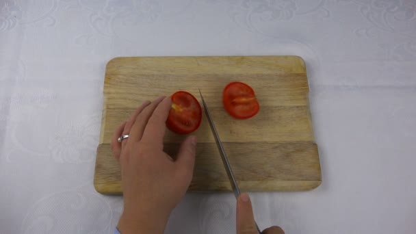 Ένα αιχμηρό μαχαίρι κόβει μια κόκκινη ντομάτα σε τέσσερα κομμάτια — Αρχείο Βίντεο