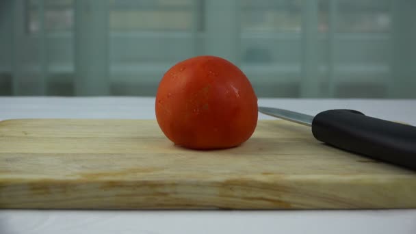 Чоловічі руки, що ріжуть помідор на дерев'яній дошці — стокове відео