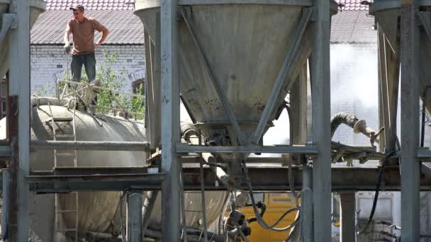 Un trabajador se para con una pala en las manos en una planta de cemento — Vídeo de stock