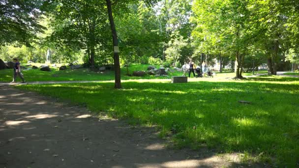 La gente camina en un parque de la ciudad con bebés en un cochecito — Vídeo de stock