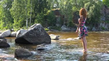 bir kız bir taş su üzerinde yalınayak standları
