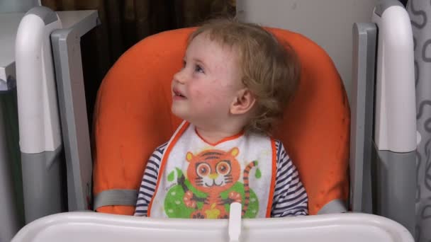 L'enfant s'assoit dans un siège d'enfant à une table — Video