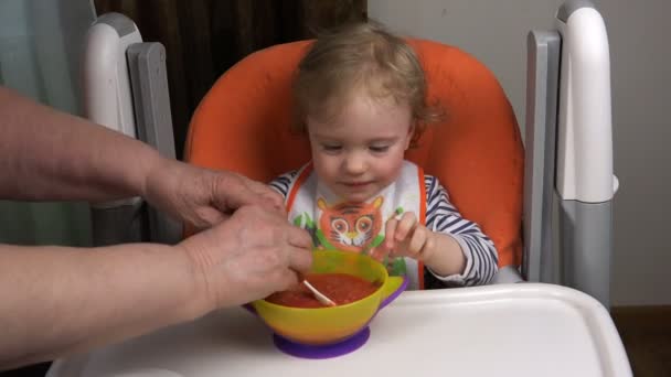 Oma maakt een kom soep aan haar kleindochter op tafel — Stockvideo