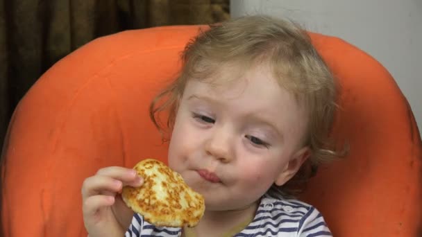 Een kind met een enorme eetlust heeft pannenkoeken aan de tafel — Stockvideo