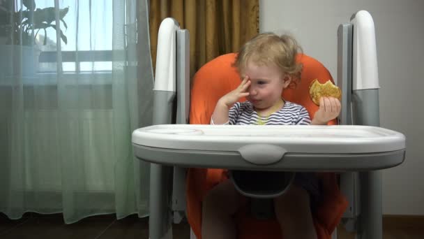 Kız kameraya konuşurken ve çocuk oyuncağı sallayarak masadaki — Stok video