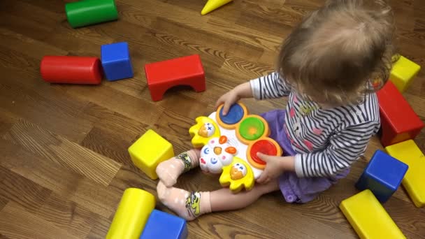 Curly luz marrom menina pressiona os botões de um brinquedo musical — Vídeo de Stock