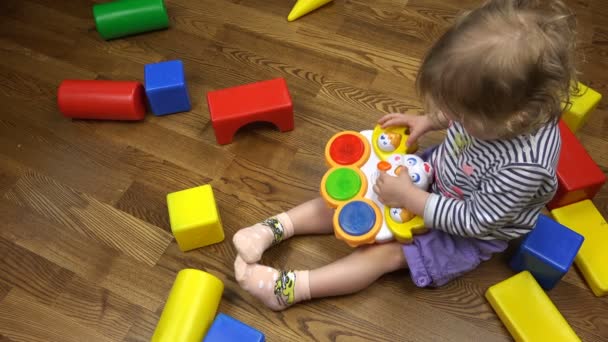 Chica en pantalones cortos morados divertirse con juguetes en el suelo — Vídeo de stock