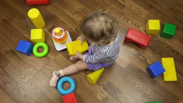 Ребенок фролики и прыжки от радости среди игрушечных фигурок различных форм — стоковое видео