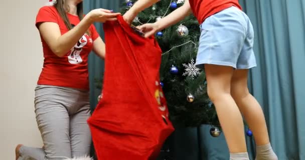 Hijo ayuda a mamá a poner regalos de Año Nuevo en una bolsa — Vídeo de stock