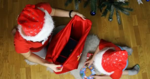 Das Schneemädchen und sein Assistent packen Geschenke in eine rote Neujahrstasche — Stockvideo