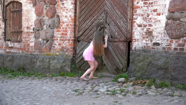 Fille avec plaisir jette un oeil dans les portes en bois fermées — Video