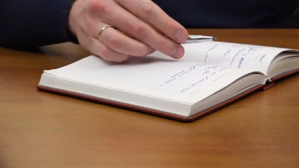 Mens mão coloca uma caneta em um caderno — Vídeo de Stock