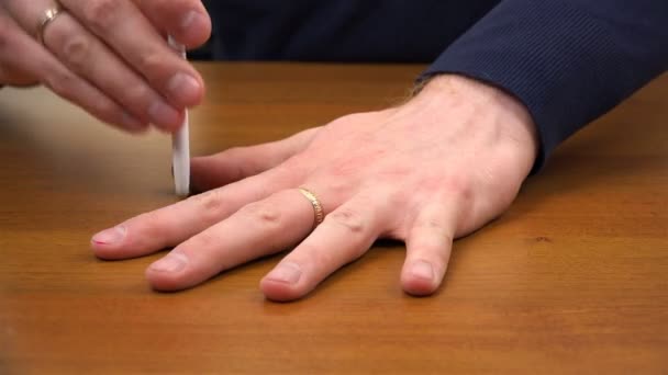 A ballpoint pen pierces the space between the fingers of the left hand — Stockvideo