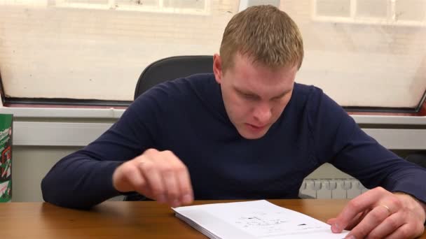Инженер читает рисунки и вытирает пот с лба рукой — стоковое видео