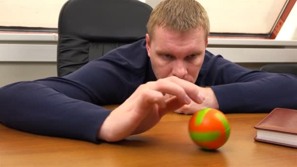 En kontorsarbetare rullar eftertänksamt en liten boll över bordet — Stockvideo