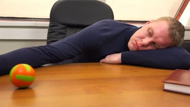 Trabalhador de escritório cansado rola uma pequena bola em toda a mesa — Vídeo de Stock