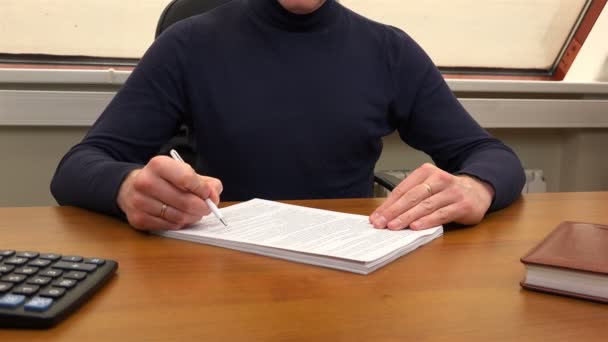 Um funcionário de escritório relê um documento em sua mesa — Vídeo de Stock