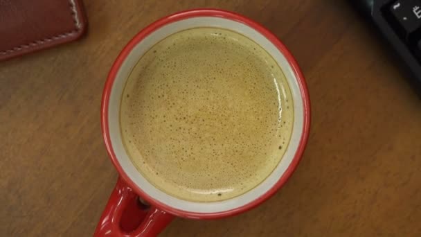 En la mesa junto al teléfono y el teclado es una taza de café rojo — Vídeo de stock