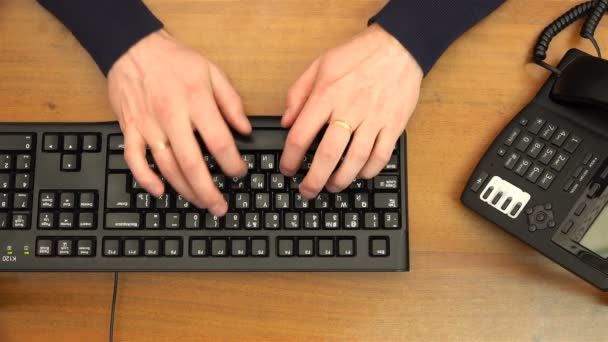 Dedos digitando no teclado preto no escritório perto do telefone — Vídeo de Stock