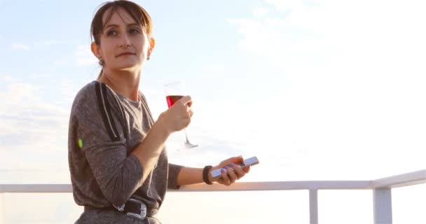 O fată cu un pahar de vin roșu stă pe puntea unei nave cu motor — Videoclip de stoc
