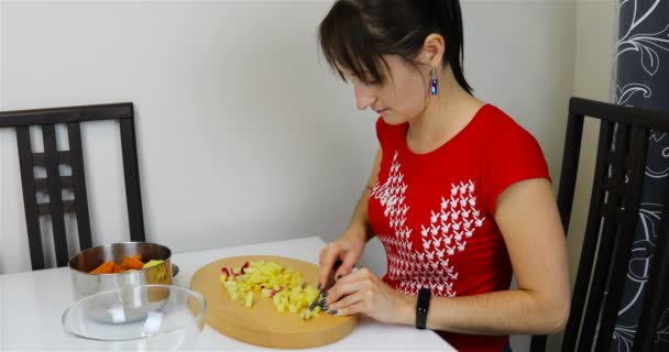 Une fille coupe des pommes de terre bouillies sur une planche — Video