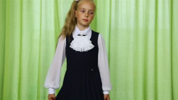 Дівчина крутиться в шкільній формі на зеленому фоні — стокове відео