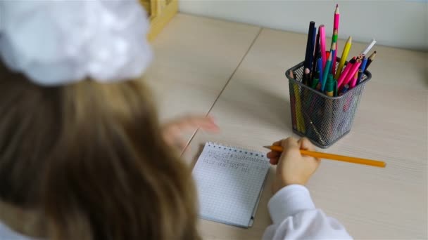Achter een bureau schoolmeisje ijverig schrijft brieven — Stockvideo