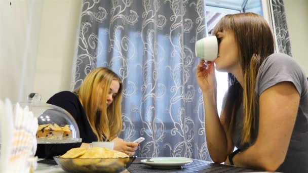 한 소녀가 식탁에 앉아 스마트폰에 메시지를 씁니다. — 비디오