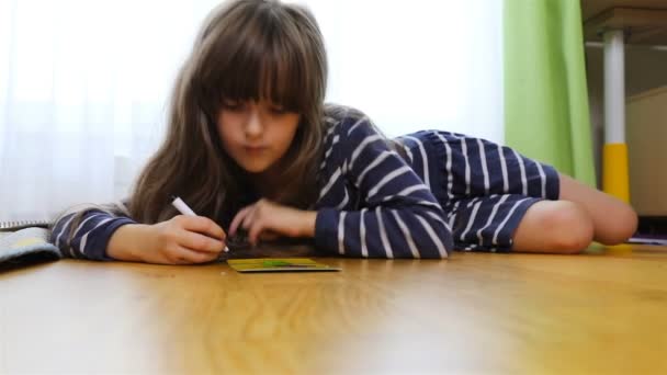 Giovane bruna disegna appassionatamente sdraiato sul pavimento — Video Stock