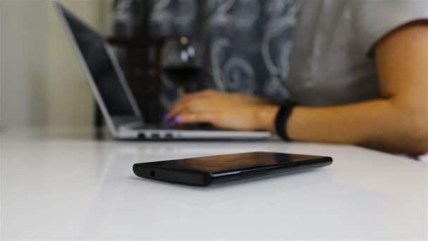Un teléfono inteligente negro se encuentra sobre la mesa de una persona de negocios — Vídeos de Stock