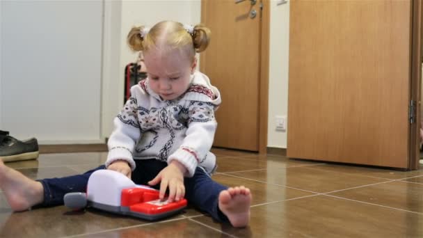 Das Mädchen mit dem Pferdeschwanz sitzt auf dem Boden im Flur der Wohnung — Stockvideo