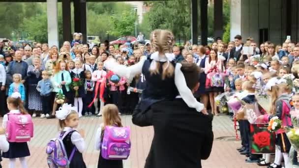 High school student bär den första-grader med klockan i famnen — Stockvideo