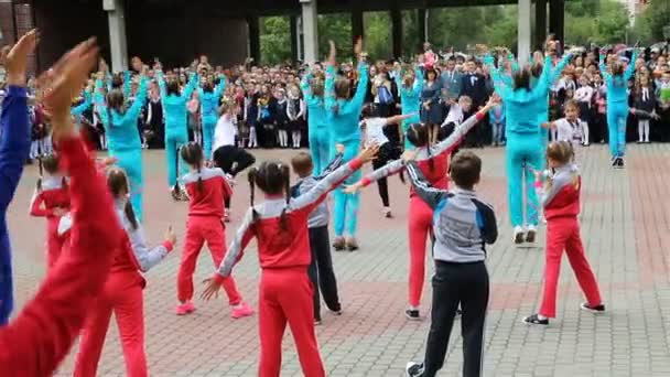 Дети в спортивных костюмах танцуют на школьном собрании — стоковое видео