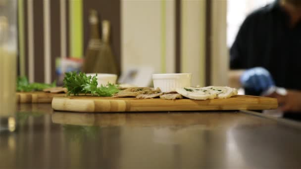 Het vleesgerecht met de saus en kruiden op het houten dienblad op de bar balie van het café — Stockvideo