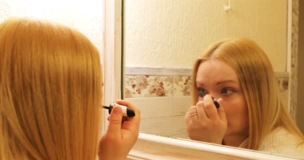 De vrouw zet de zwarte mascara zorgvuldig op haar wimpers — Stockvideo