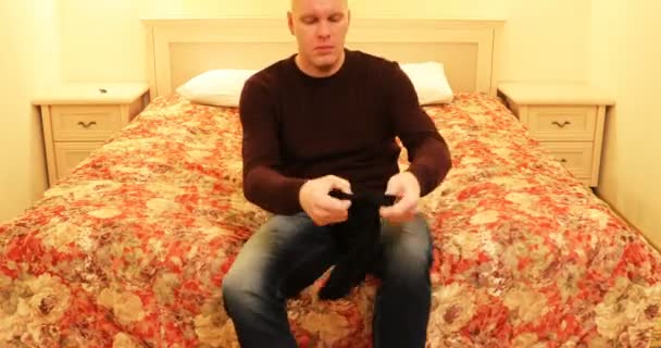 De man zet zwarte sokken op zijn benen — Stockvideo