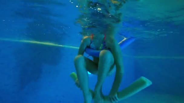 Kız köpük çubuğu kullanarak yüzmeyi öğreniyor. — Stok video