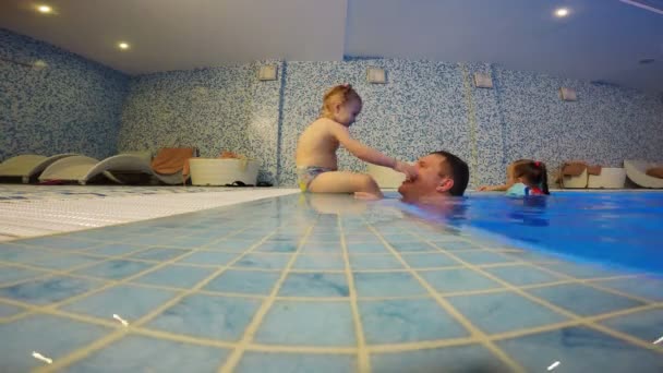 Padre y su hija están jugando en la piscina — Vídeo de stock